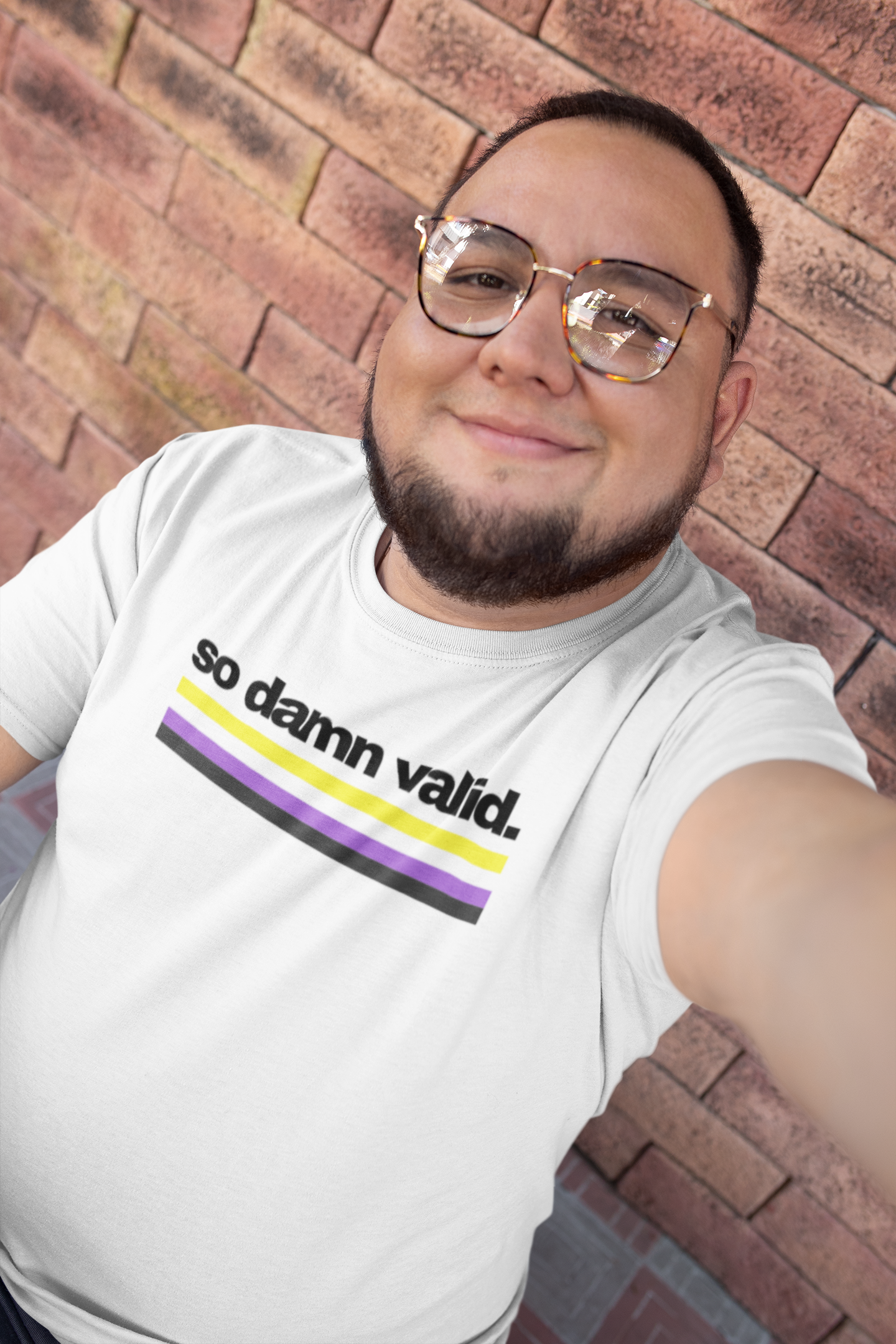 Unisex white t-shirt with the phrase "so damn valid." in black text above horizontal nonbinary pride stripes in yellow, white, purple, and black.