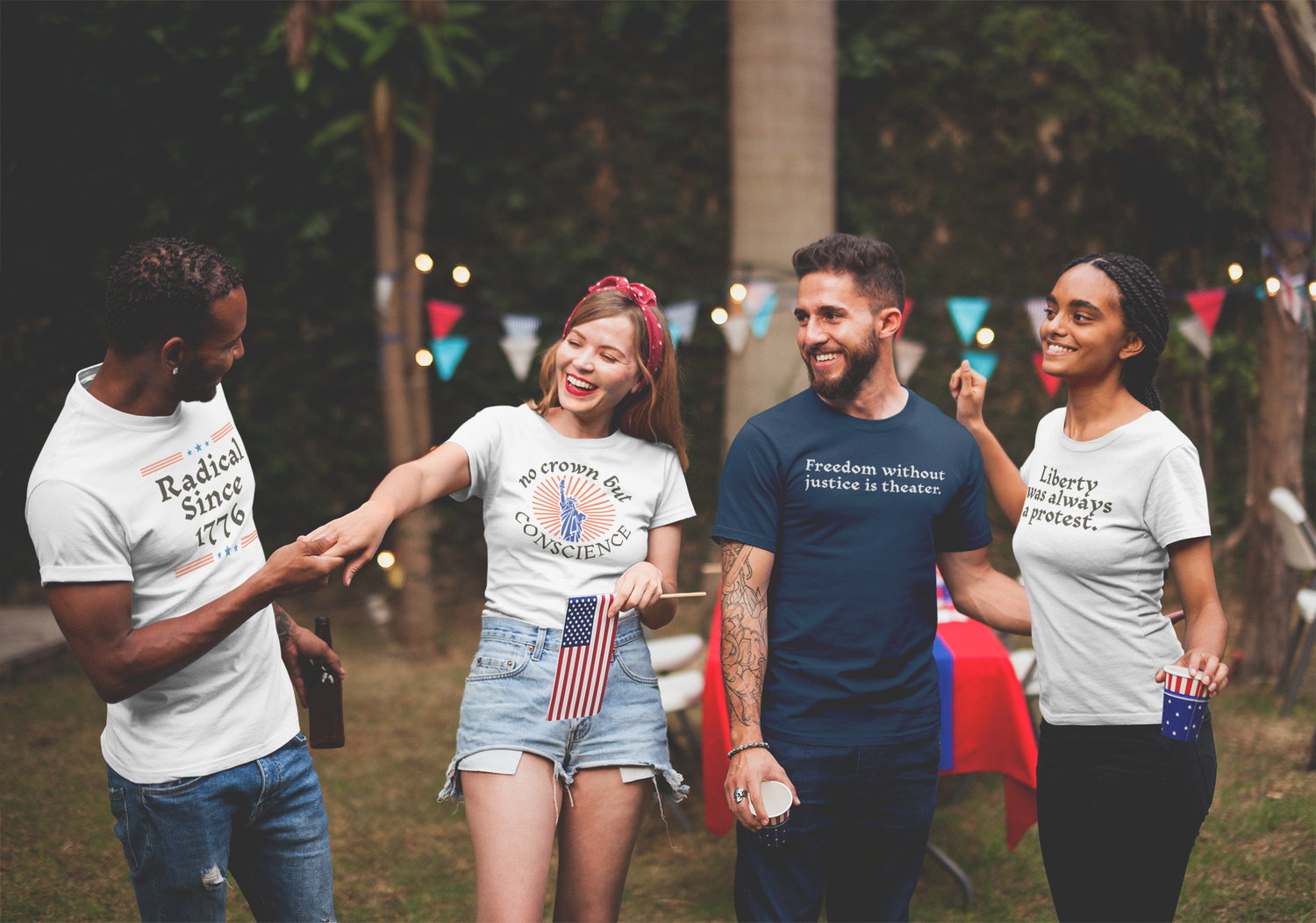 A diverse group of friends laugh and chat at an outdoor gathering, wearing political statement t-shirts with slogans like “Radical Since 1776” and “Liberty was always a protest,” surrounded by patriotic decor and string lights.