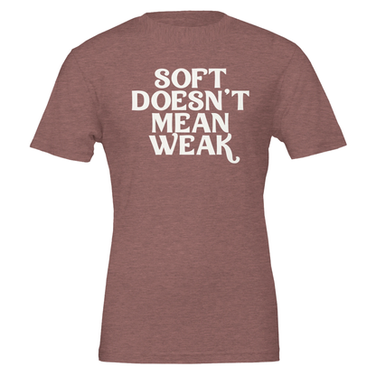 Flat lay of heather mauve t-shirt with white retro-style lettering saying “Soft Doesn’t Mean Weak.”