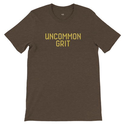 Flat lay of the Uncommon Grit Legacy Edition tee in Heather Brown with bold gold text on the chest.